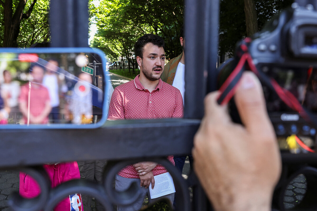 Mahmoud Khalil, in a short-sleeved shirt, speaks to reporters outdoors.